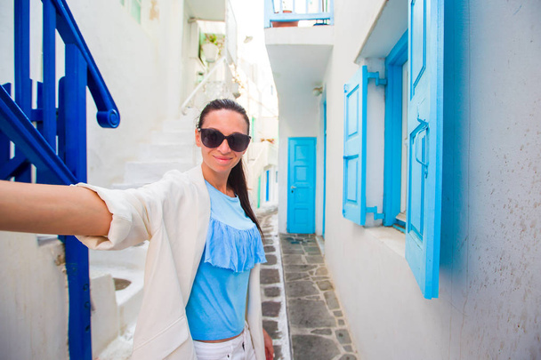 Gelukkige vrouw nemen selfie op verlaten straten van Grieks dorp. Jonge mooie vrouw op vakantie verkennen Europese stad - Foto, afbeelding