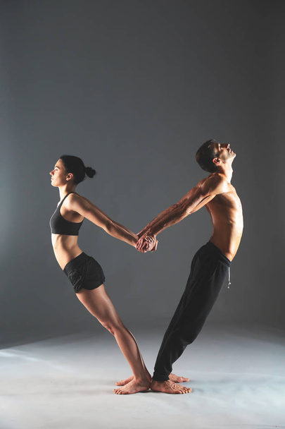 Young couple practicing acro yoga on mat in studio together - Foto, Imagem