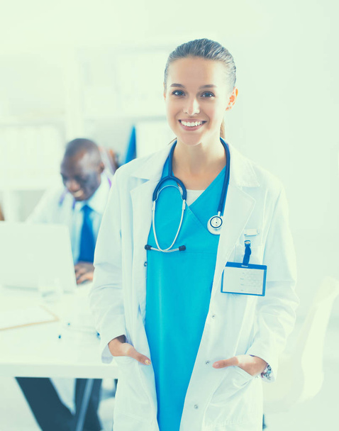 A smiling female doctor with a folder in uniform indoors - Foto, Imagem