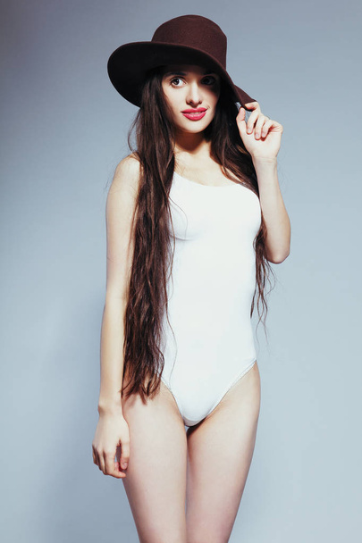 Όμορφη κοπέλα με μακριά μαλλιά με λευκό κοστούμι σώμα και καπέλο - Φωτογραφία, εικόνα