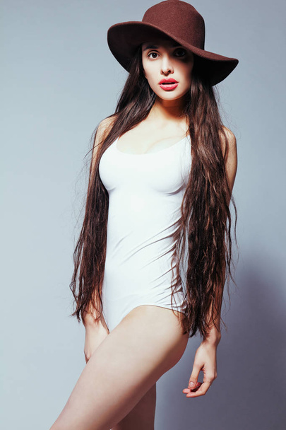 Menina bonita com cabelos longos em um terno corpo branco e chapéu
 - Foto, Imagem