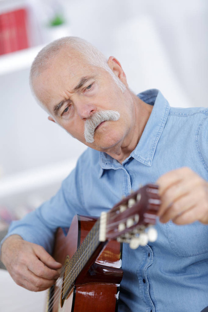 an elderly man playing an acoustic guitar - Foto, imagen