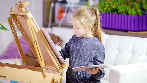 Entzückendes kleines Mädchen malt ein Bild auf Staffelei drinnen - Filmmaterial, Video
