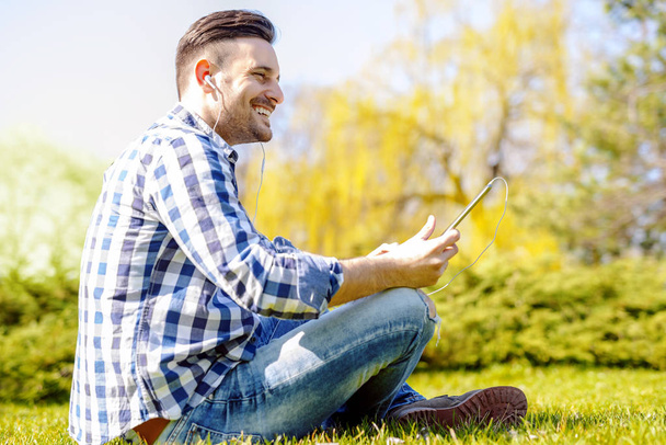 Fiatal férfi ült a szabadban hallgató-hoz zene - Fotó, kép