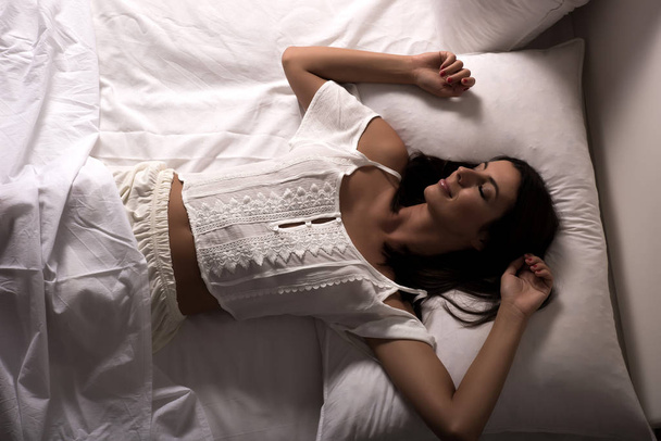 Beautiful woman laying in the bed at night - Foto, afbeelding