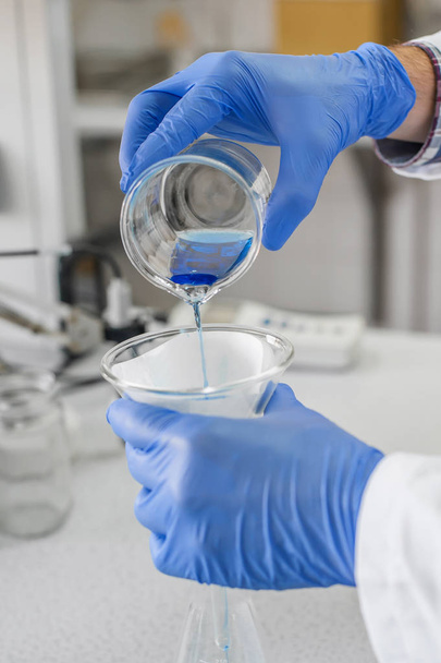 Laboratory technician performs tests and pouring blue liquid - Foto, Imagem