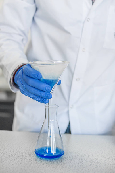 Laboratory technician performs tests and pouring blue liquid - Photo, image