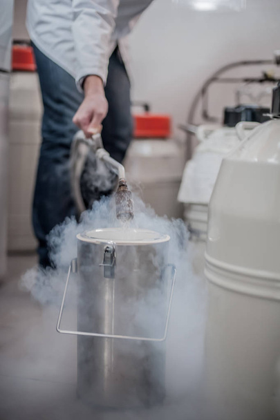 Liquid nitrogen technician fills cryogenic container - Foto, imagen