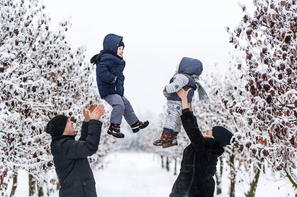 Happy parents throws up baby son and girl in winter park outdoor - Valokuva, kuva