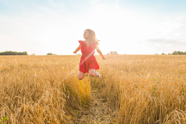 Woman jumps to the sky in yellow field at sunset - Photo, image