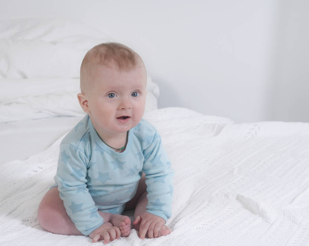Babyportrait of cute little happy baby boy sitting on the bed - Fotografie, Obrázek