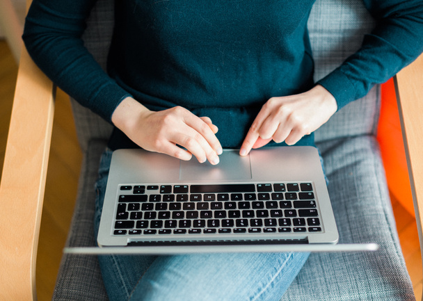 Femme réfléchie portant un pull bleu travaillant sur un ordinateur portable - vue d'en haut
 - Photo, image