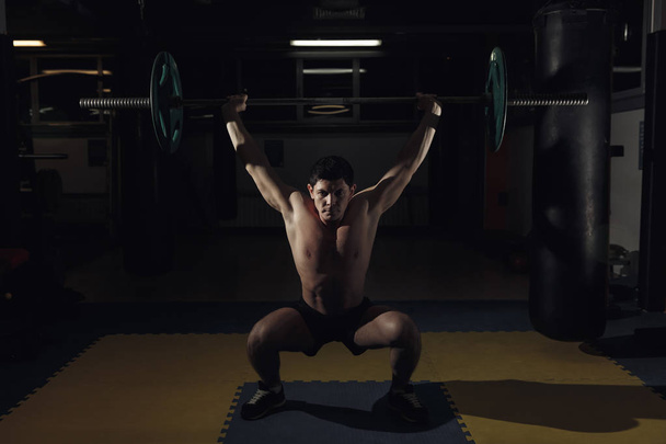 Hombre musculoso en un gimnasio crossfit levantando una barra. - Foto, imagen