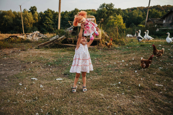 a little girl standing near an old car with a doll - Fotó, kép