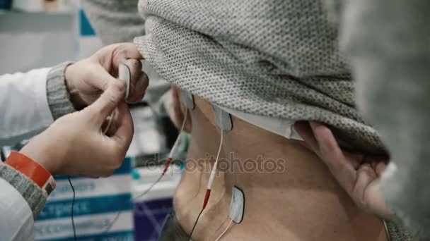 Nahaufnahme Krankenschwester installiert Ausrüstung auf dem Rücken des Patienten, professionelle Elektrotherapie am Körper des Mannes. - Filmmaterial, Video