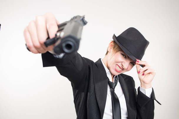 girl gangster holding a gun. Classic suit and hat. - 写真・画像