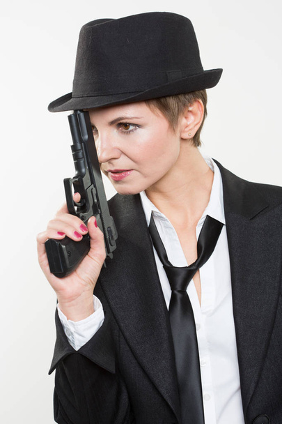 girl gangster holding a gun. Classic suit and hat. - Fotó, kép