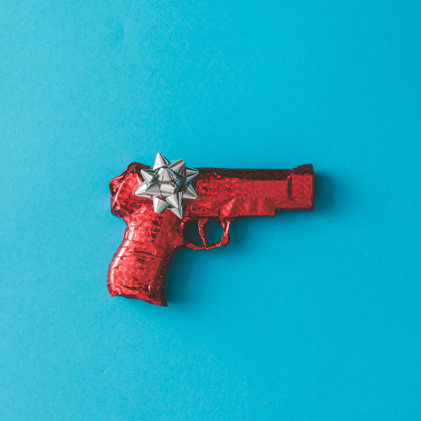 Pistola envuelta en papel rojo con lazo
  - Foto, Imagen
