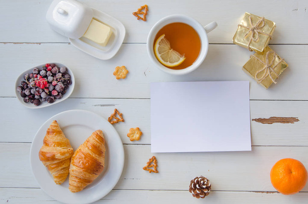 Reggeli forró croissant, vaj, tea és mazsola, a fából készült asztal. Lapos feküdt - Fotó, kép