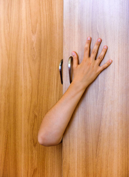 Person hand protruding from wardrobe door - Valokuva, kuva