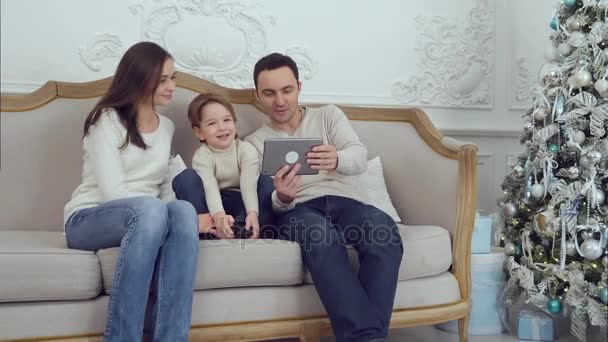 Young happy family using tablet on the sofa - Záběry, video