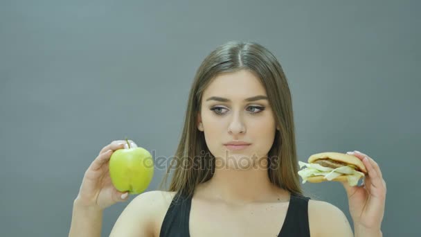 hard choice: apple or burger, flustered girl decided to go on a diet - Video, Çekim