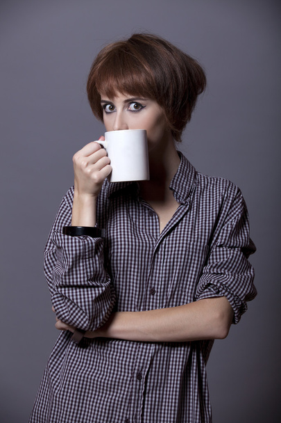 Style girl in shirt with cup at studio. - Zdjęcie, obraz