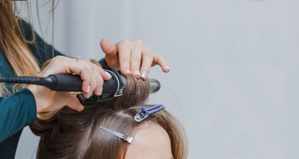 stylist making ringlets to brunette woman. Hairdresser working w - Photo, Image