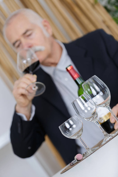 senior man tasting wine thinking deeply on life - Foto, afbeelding