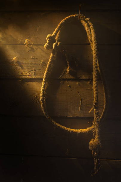 古い納屋の中の薄明かりの中でぶら下がっているロープを古く埃っぽい. - 写真・画像