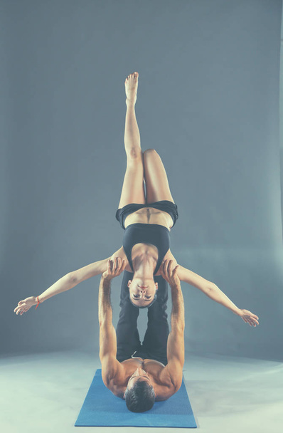 Young couple practicing acro yoga on mat in studio together - Foto, Imagen