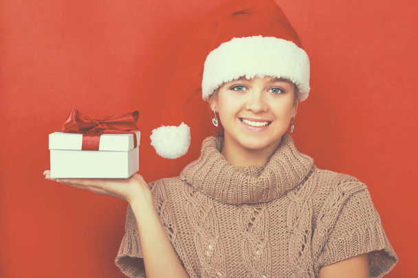 Santa girl holding Christmas gift on red background - Foto, Bild