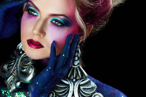 Young attractive blonde girl in bright art-makeup, high hair, body painting. Rhinestones and glitter - Фото, зображення