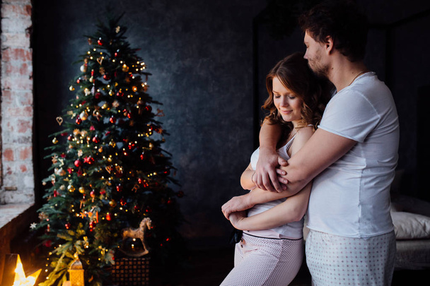 couple in pajamas on Christmas tree background - Фото, зображення