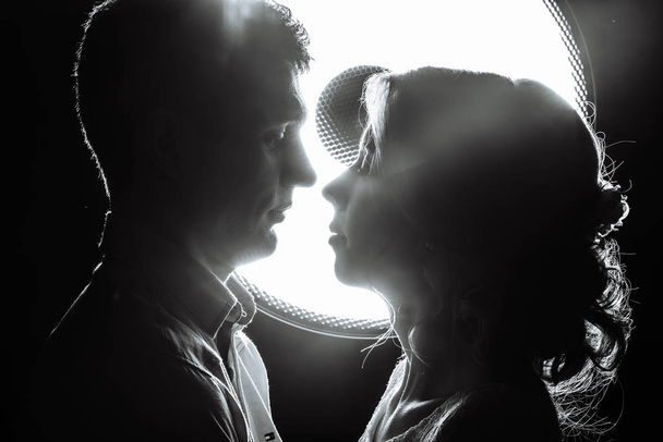 αγαπώντας άνδρας και γυναίκα στις ακτίνες του φωτός σε μαύρο φόντο - Φωτογραφία, εικόνα