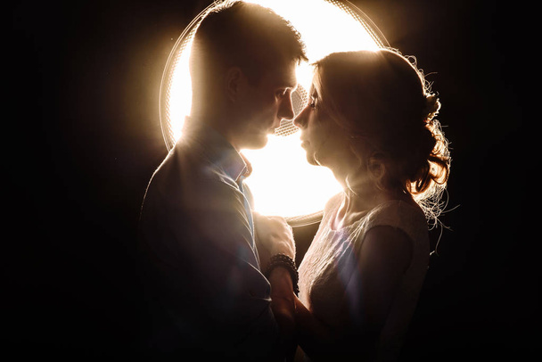 loving man and woman in the rays of light on a black background - Photo, Image