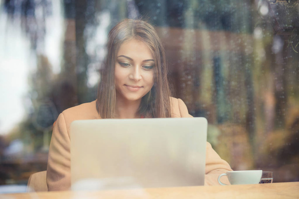 Charming woman looking on laptop during rest in coffee shop, happy  - Photo, Image