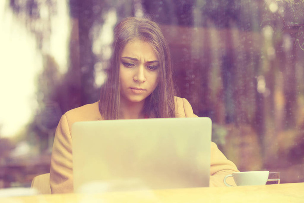 Kobieta zdenerwowany, siedząc w kawiarni przed laptop przytrzymanie ekranu w ręce - Zdjęcie, obraz