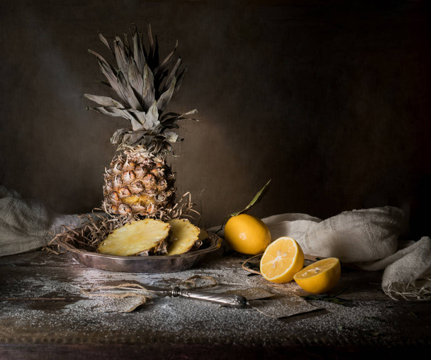 still life. pineapple, lemon, tropical juice, old silver knife on a wooden table - Foto, imagen