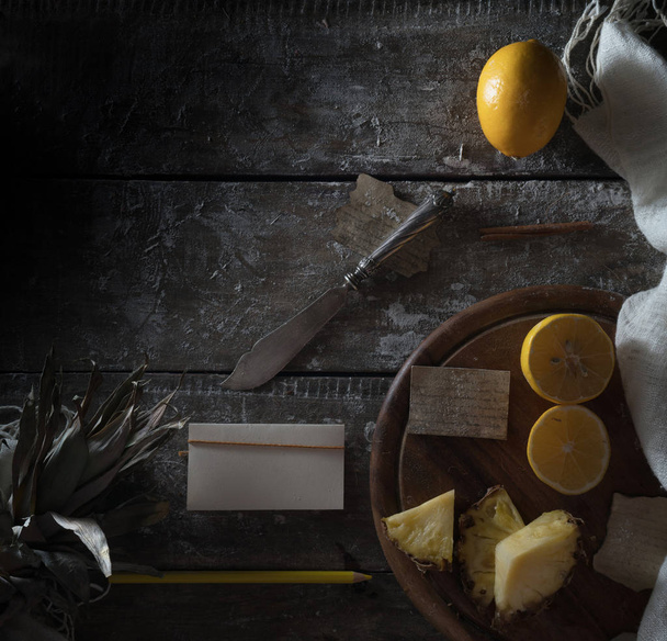 pineapple, lemon, pencil, old silver knife on a wooden table. top view - Fotografie, Obrázek