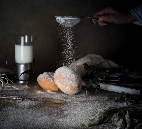female hand sifts the flour on a wooden table. dark background, vintage - Fotó, kép