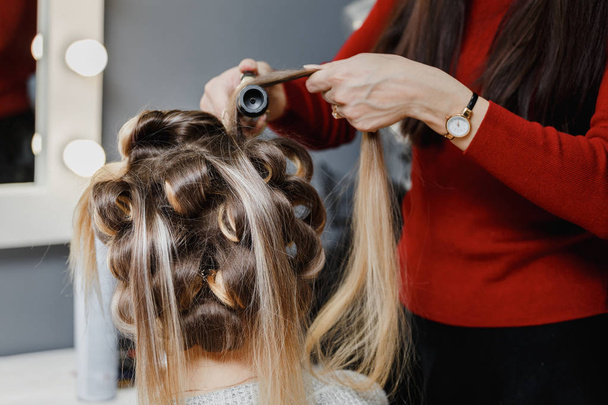 stylist making ringlets to brunette woman. Hairdresser working w - Photo, Image