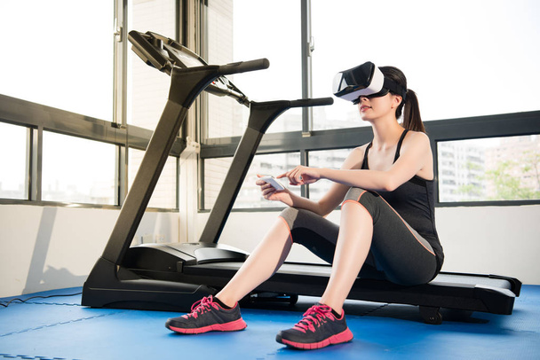 woman rest treadmill with VR headset control by smartphone - 写真・画像