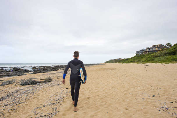 Surfer walks along beach with surfboard - Foto, Imagem