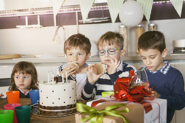 happy kids celebrating around a cake for a birthday - Fotó, kép