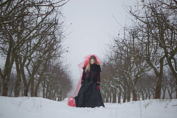 Dziewczyna w czerwonym welonem na śniegu w zimie - Zdjęcie, obraz