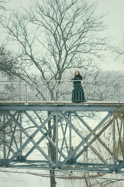 beautiful girl standing on the pedestrian bridge in winter - Foto, Imagen