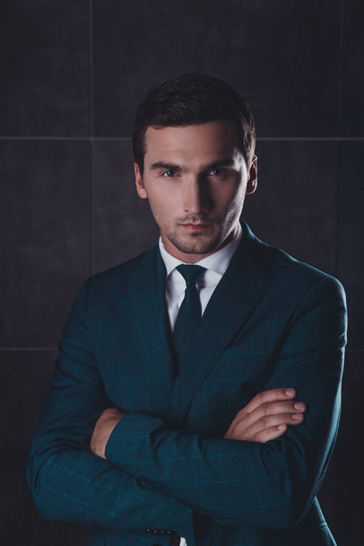 Portrait of serious young businessman in black suit with crosed  - Foto, immagini