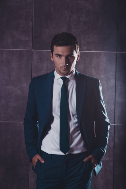 Handsome young businessman in suit holding hands in pockets - Foto, afbeelding