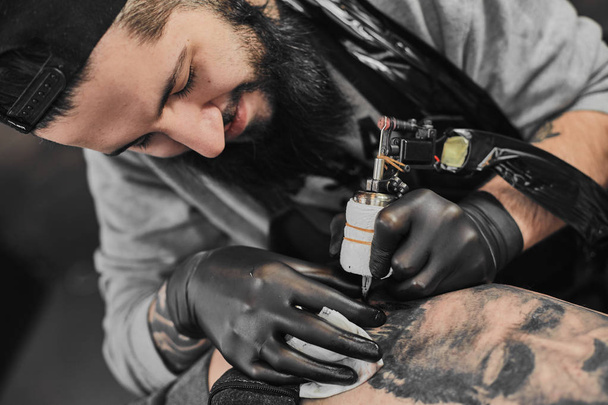 Tattoo master is tattooing in the tattoosalon - Foto, afbeelding